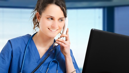 Clinician speaking on telephone whilst looks at a computer screen